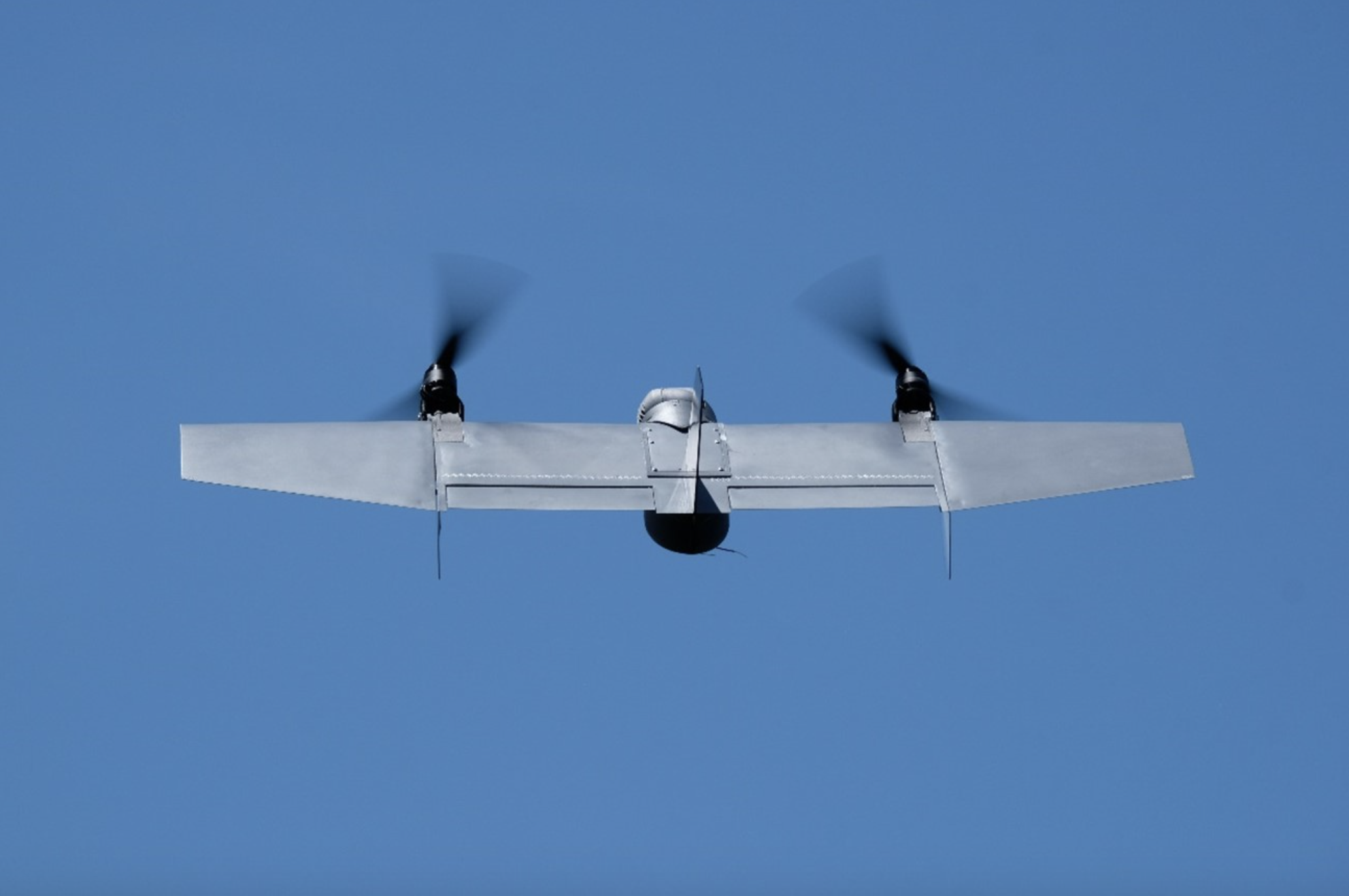 A drone mid-flight against a blue sky