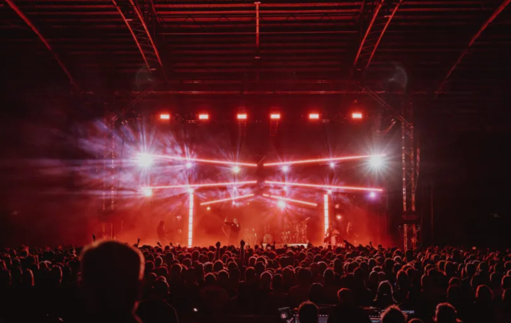 a concert in a large venue with red lighting and large crowd