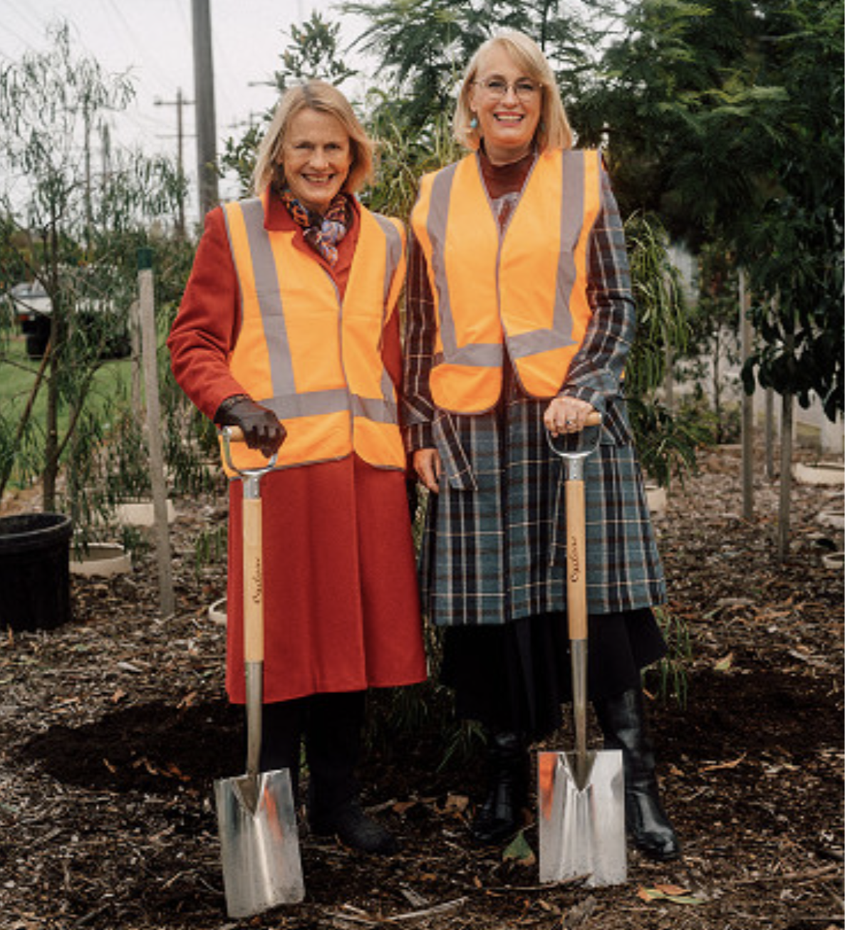 Meredith Sussex – Chair of Fishermans Bend Development Board and Lord Mayor Sally Capp break ground to plant trees along Turner Street holding shovels and wearing hi-vis vests