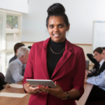 An Aboriginal Australian woman in an office setting holds a computer tablet